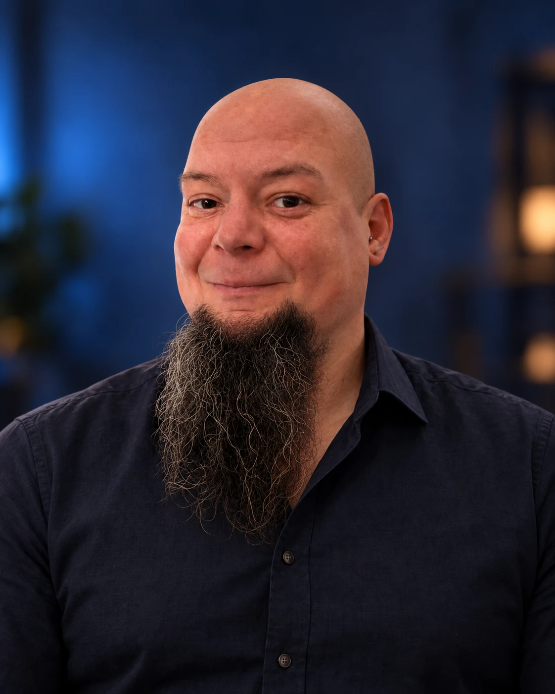 Adam, the designer behind Prowebdsgn, with a shaved head and long beard, smiling in a dark navy shirt